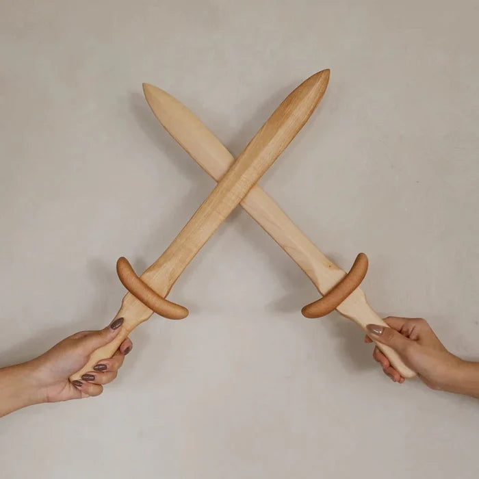 Two hands holding crossed wooden swords against a plain background