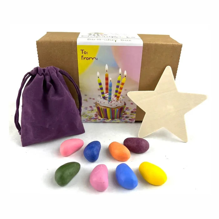 To/From box with rock-shaped crayons next to a purple velvet bag and a wooden star on a white background