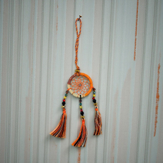 Dreamcatcher with orange and black tassels on a striped background