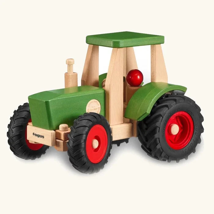 Wooden toy tractor with green body, black wheels, and red details on a white background