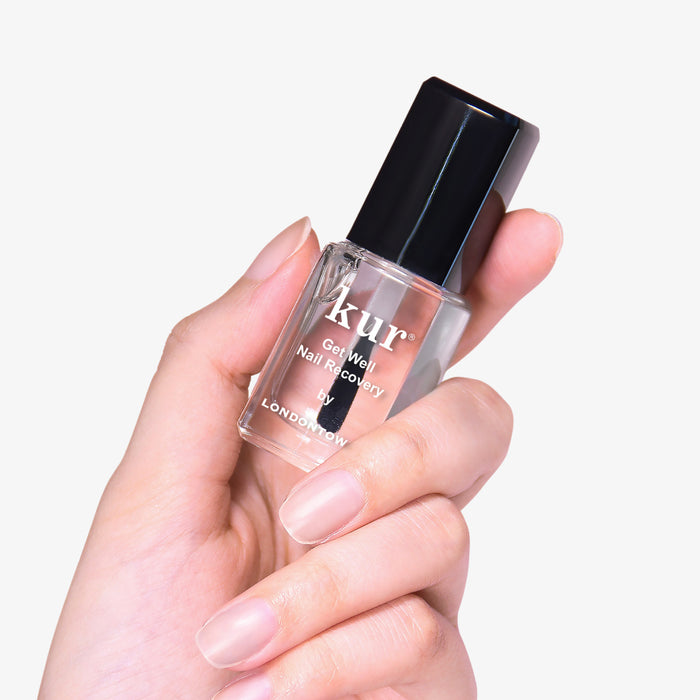 A hand holds a bottle of Get Well Nail Recovery by LONDONTOWN, with a black cap and transparent liquid. It's perfect for restoring damaged nails and nurturing ultra-weak nails against a pristine white background.