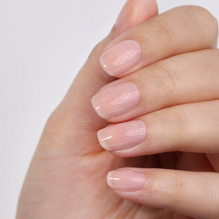 A hand with glossy pale pink nails, manicured to perfection with LONDONTOWN's Get Well Nail Recovery, showcases nail rehab on ultra-weak nails.