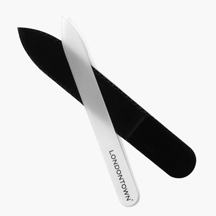 The Glass Nail File - White by LONDONTOWN, placed next to a black sheath, ensures effortless nail filing without damage.