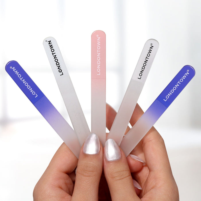 A person holds five LONDONTOWN Glass Nail Files in various colors, including blue gradient, pink, and clear, ensuring effortless and damage-free nail filing.