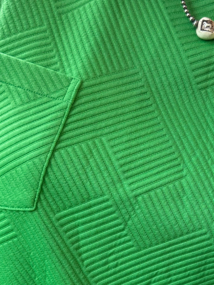 Kelly green textured fabric knit with raised geometric pattern close-up