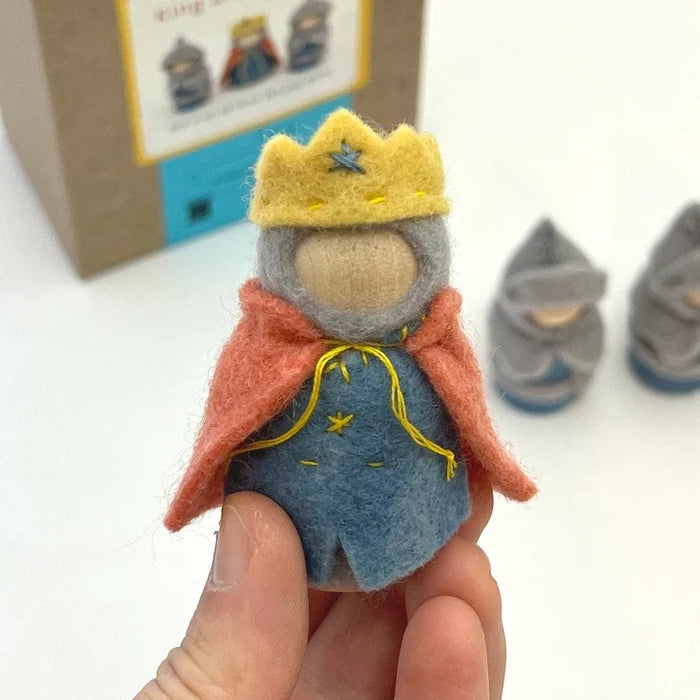 Small felt figurine of a king held by a hand, with a cardboard box in the background.