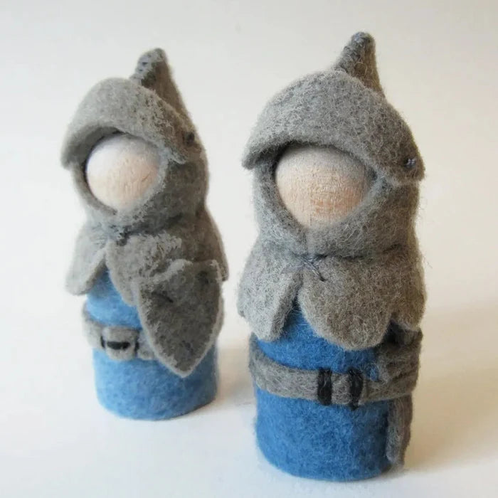 Two felted knights wearing gray hooded cloaks and blue outfits on a white background
