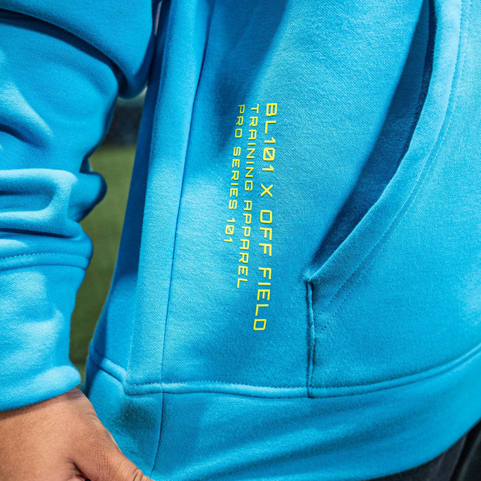 Close-up of a blue hoodie with yellow 'BL101 X OFF FIELD' text on the side.