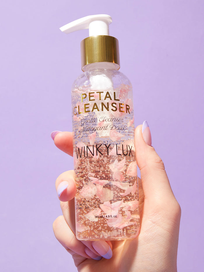 hand holding up petal face cleanser on purple background