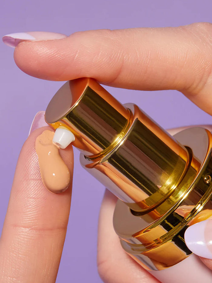 close up of finger pumping product out of tinted moisturizer bottle