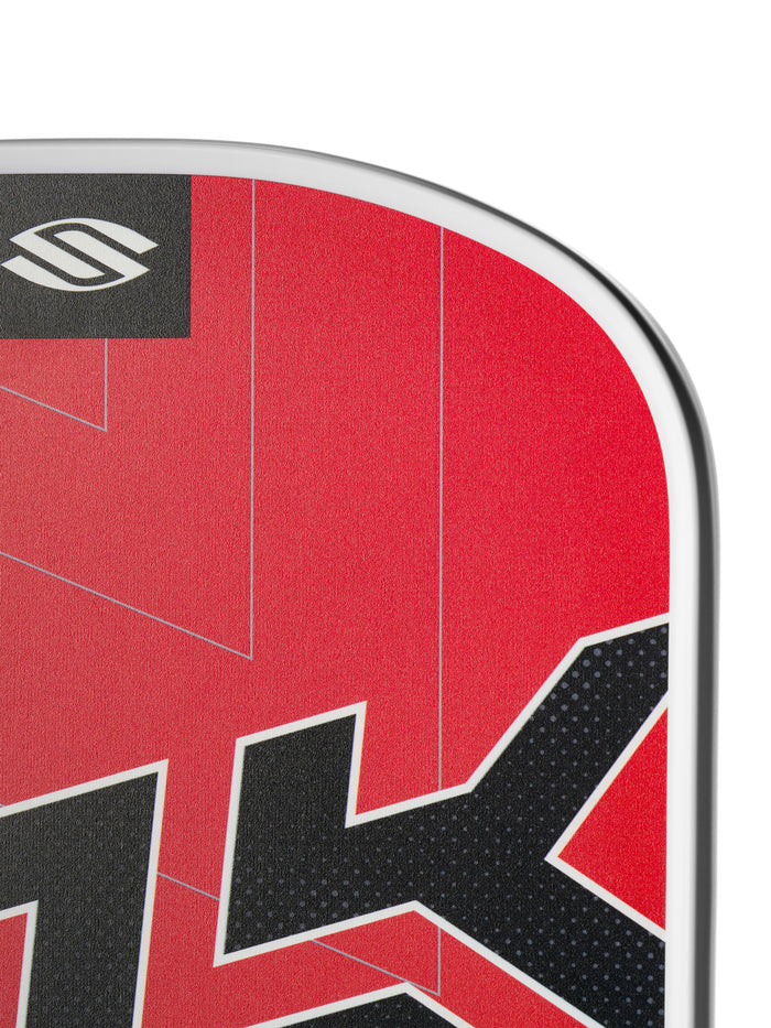 Close-up corner of SLK Prime 2.0 widebody pickleball paddle showing red textured face, black SLK lettering, and white edge guard