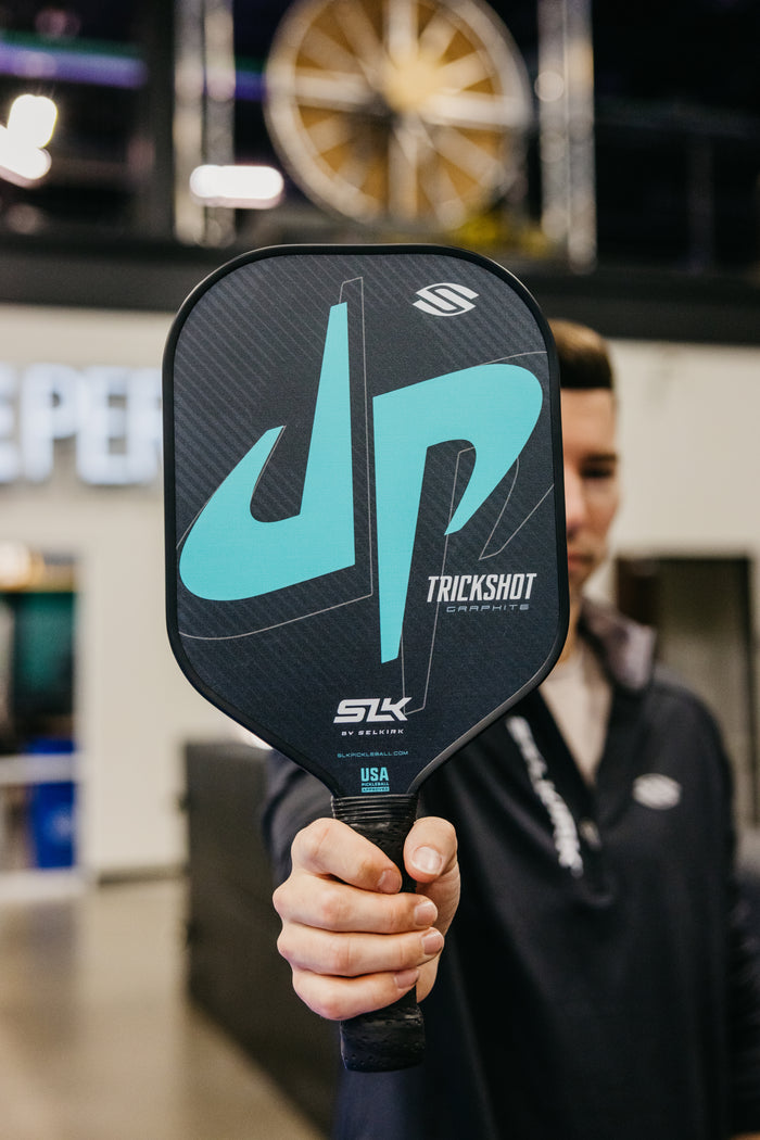 Pickleball paddle face with turquoise 'JP' logo and the words TRICKSHOT, GRAPHITE, SLK, BY SELKIRK, USA.
