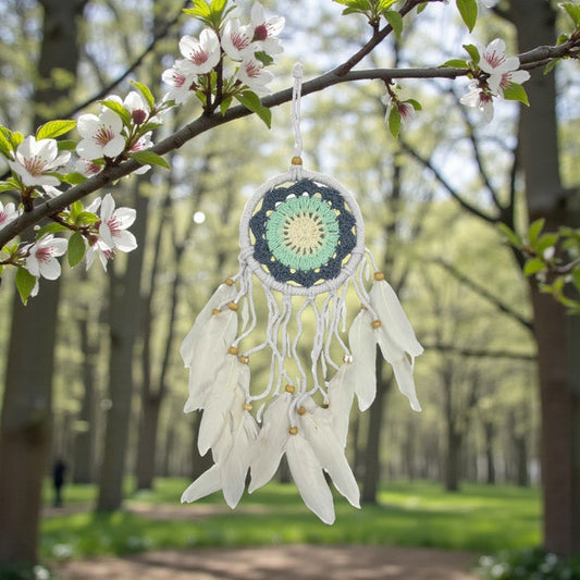 Dreamcatcher hanging from a tree branch with flowers in a park setting