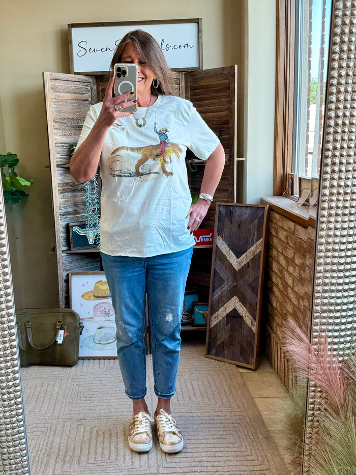 Light blue T-shirt with cowboy riding a dinosaur graphic on the front