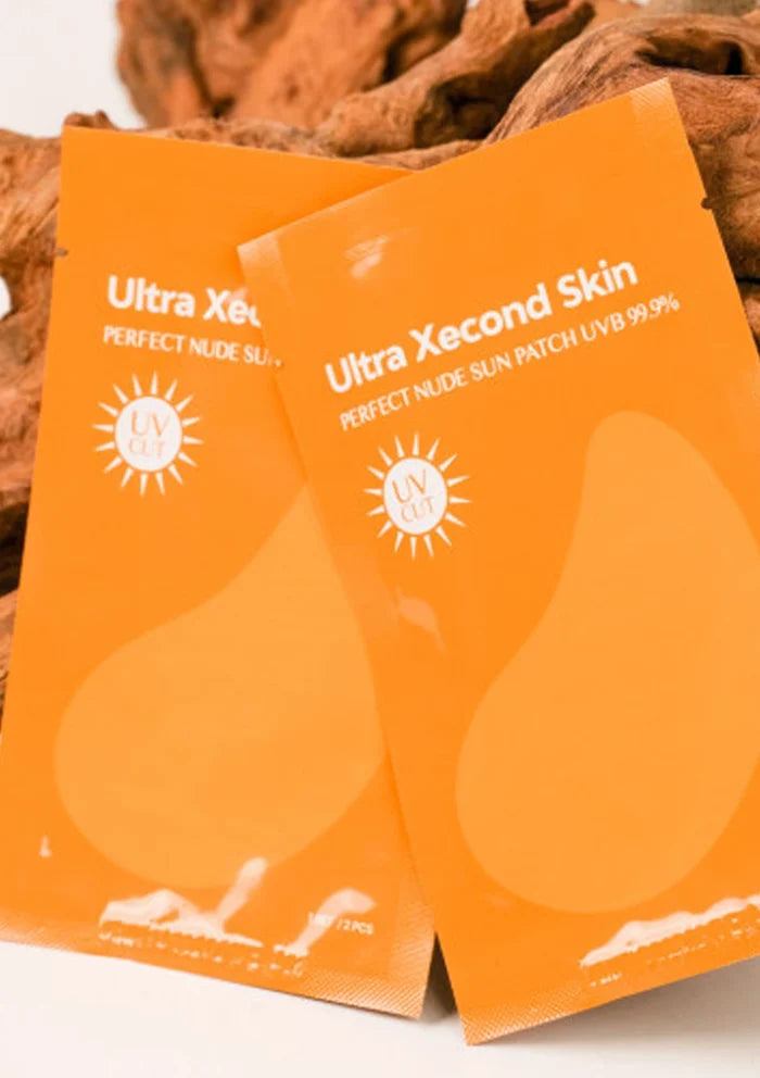 Two orange packages of Ultra Xecond Skin sun patch with a blurred background.
