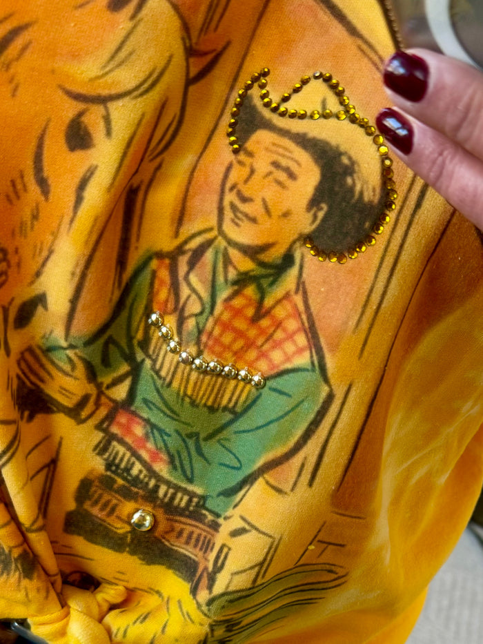 Close-up: yellow sweatshirt with cowboy and horse rhinestone accents