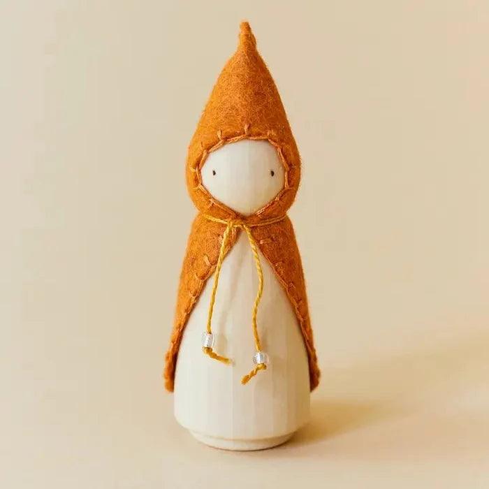 Wooden gnome figure with an orange hood and coat on a beige background