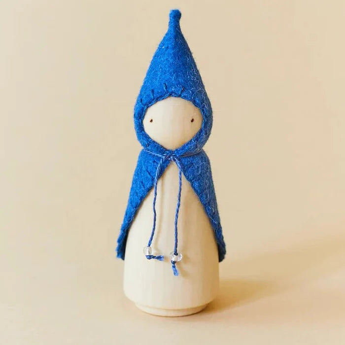 Wooden gnome figure with a blue hood and coat on a beige background